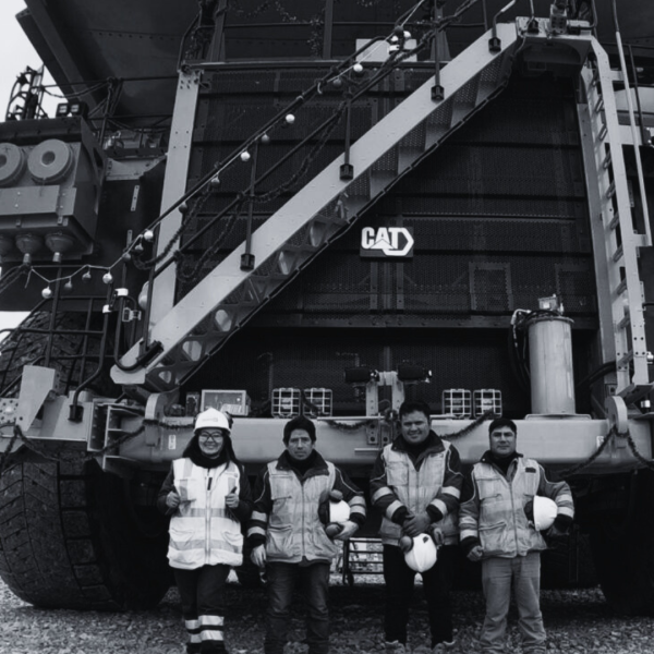 Ferreyros CAT Chooses AFEX A black and white photo of a large CAT haul truck with four miners standing in front of it